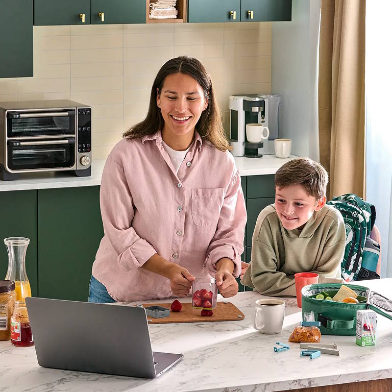 consultant with a child cooking a meal while looking at a laptop computer