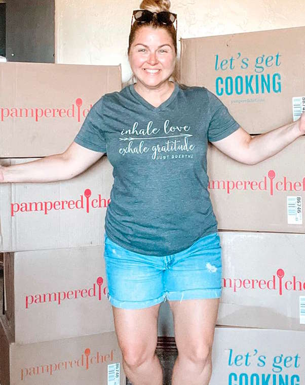 a consultant standing in front of a wall of pampered chef boxes