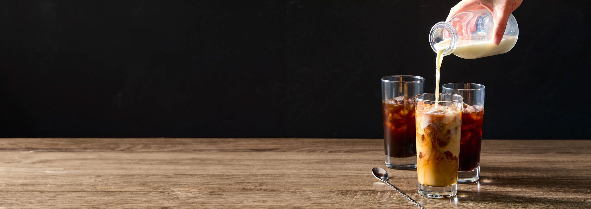 Pouring milk into iced coffee