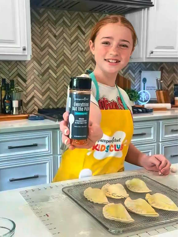 A mom posting next to her son who’s wearing the Kids Club Apron with Cool Pizza Pin and holding a Kids Club box.