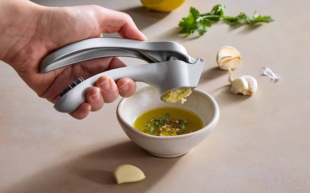 Someone pressing garlic with the Garlic Press