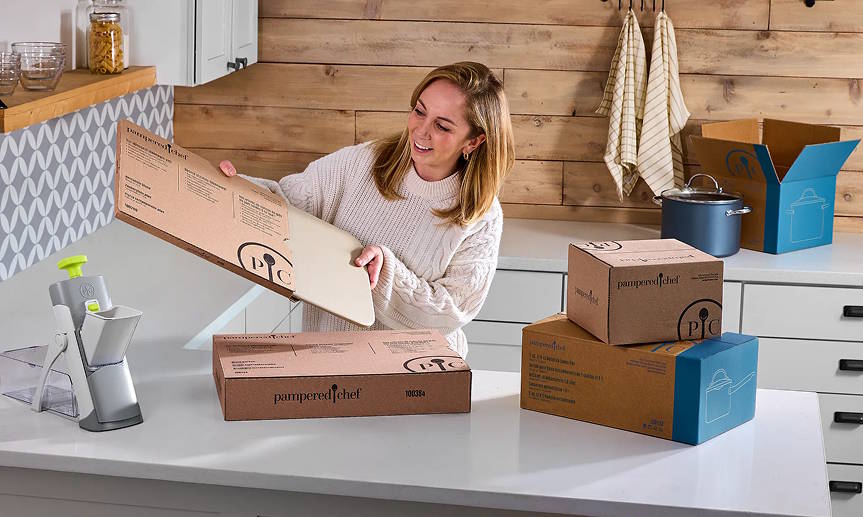 a party host opening Pampered Chef boxes in her kitchen