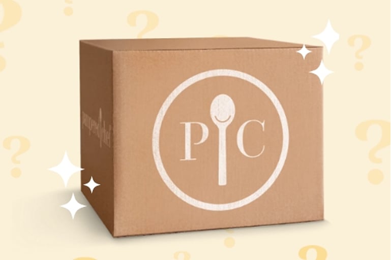 a mysterious, enticing looking box with the pampered chef logo on it and question marks in the background.