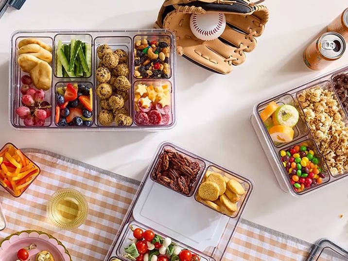 various snacks in multiple snackle boxes. Also, there's a baseball glove with a baseball in it.