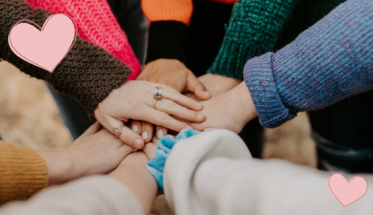 circle of hands, with all people wearing knitted sweaters.
